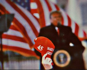 Photo edit of a Trump supporter holding a MAGA hat. Credit: Alexander J. Williams III/Popacta.